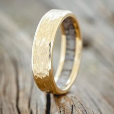 a gold wedding ring sitting on top of a wooden table