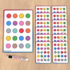 two sheets of colored dots next to a marker and pen on a wooden table with markers