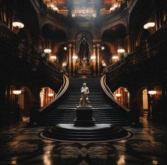 a statue sitting on top of a set of stairs in a building with chandeliers hanging from the ceiling