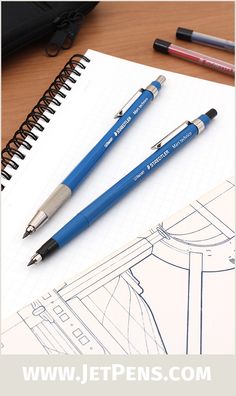 two pens sitting on top of a piece of paper next to a notebook and pen