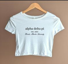 Alpha Delta Pi Basic Cropped Tee Key Features Stylish Design: This cropped tee offers a modern and chic silhouette that pairs perfectly with high-waisted jeans, skirts, or shorts. Comfort: Made from soft, breathable fabric, this tee ensures maximum comfort all day long, whether you're attending classes, hanging out with sisters, or just lounging around. Alpha Delta Pi Branding: Proudly display your ADPi pride with this essential piece, featuring the iconic Alpha Delta Pi lettering. Benefits Comf Spring Letter Print Stretch Crop Top, Spring Stretch Crop Top With Letter Print, Fitted Letter Print Cropped Shirt For Spring, Spring Letter Print Stretch Cropped T-shirt, Spring Stretch Cropped T-shirt With Letter Print, Summer Cropped Shirt With Text Print, Fitted Cropped Shirt With Letter Print, Spring Cropped T-shirt With Text Print, Fitted Cropped Shirt With Letter Print And Short Sleeves