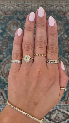 a woman's hand with three different rings on her fingers and one ring in the middle