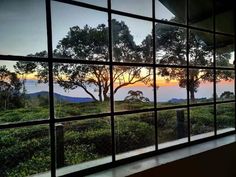 the view from an open window at sunset with trees and mountains in the back ground