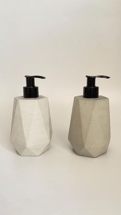 two white soap dispensers sitting next to each other on a white surface