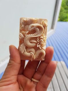 a hand holding a carved soap block with a dragon on it