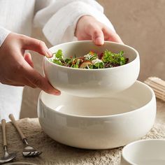 a person is holding a bowl over two plates