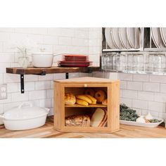 an open cabinet in the middle of a kitchen with plates and bowls on top of it