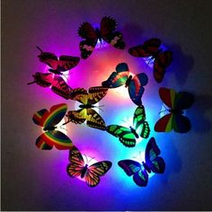 colorful butterflies are arranged in a circle on a white wall with purple and blue lights