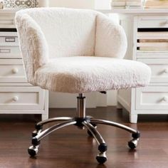 a white chair sitting on top of a wooden floor next to a desk with drawers