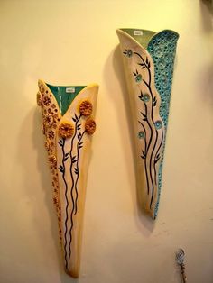 two decorative vases are hanging on the wall