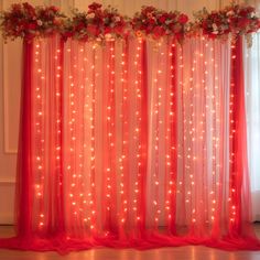 a red curtain with lights and flowers on it