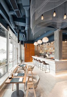 an empty restaurant with lots of tables and chairs in front of large windows that look out onto the water