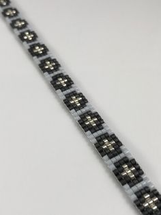 a black and white bracelet with silver beads on it's end, sitting on a table