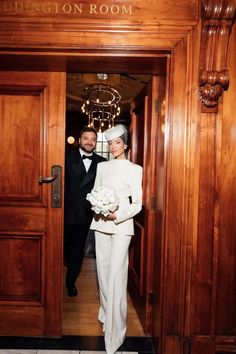 a man and woman in formal wear are walking out the door to their wedding reception