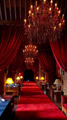 a red carpeted hall with chandeliers and lamps on either side of it