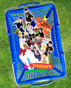 a blue basket filled with lots of stickers on top of green grass next to a field