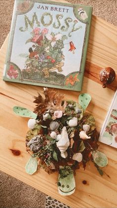 an arrangement of flowers on a table next to a book