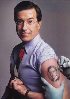 a man with a tattoo on his arm holding a scissor and wearing gloves