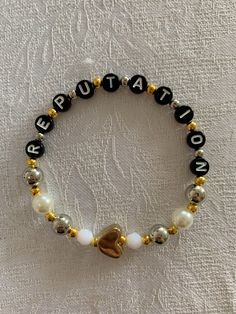 a black and white beaded bracelet with gold heart charms on it's side