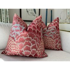 two red pillows sitting on top of a white couch