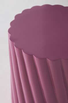 a close up of a pink vase on a white table top with lines in the background