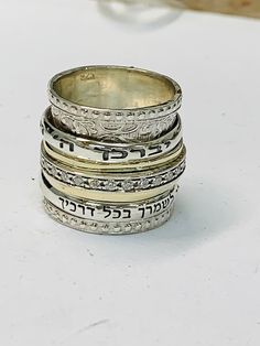 "9K Gold and sterling silver spinner ring with the Hebrew inscription reads: \" יברכך ה וישמרך (The Lord Bless You & Keep You) כי מלאכיו מצוה לך לשמרך בכל דרכיך ( the angels of god will protect you all your ways) Details: ♦ Returns accepted ♦ Materials: Sterling silver 925, 9k yellow gold ♦ Ring Width: 0.63 inches // 17mm ♦ All of my designs are handmade. ♦ Arrives in an elegant gift package. ♦ Not sure what size you need? Check this link: http://findmyringsize.com. You have the option to ch Silver Engraved Ring Stamped 14k For Promise, Silver Stackable Wedding Rings Stamped 14k, Wide Band Stamped Rings For Anniversary, Silver Sterling Engraved Ring For Marriage, Silver Promise Ring Stamped 14k, Silver Engraved Ring Stamped 14k For Anniversary, Silver Wide Band Ring For Promise, Silver Wide Band Round Ring For Promise, Wedding Engraved Ring, Stamped 925, Wide Band