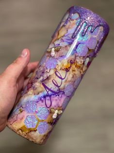 a hand holding a cell phone case with purple and gold designs on the outside, that says love