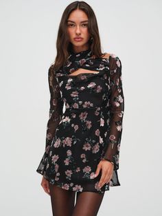 The Blake black mini dress is the epitome of elegancecrafted in an allover burnout floral fabric that exudes a demure sophistication. This short black dress features a crossover chiffon halter detail, a cowl neckline, and long, romantic bell sleeves.