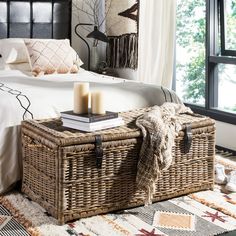 a wicker trunk sitting on top of a rug next to a bed in a bedroom