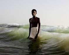 a man standing in the ocean with his surfboard