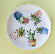 a plate with cactus designs painted on the front and sides, sitting on a yellow surface