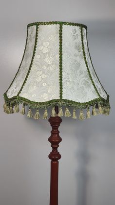 a lamp that is sitting on top of a wooden stand with a green and white lampshade