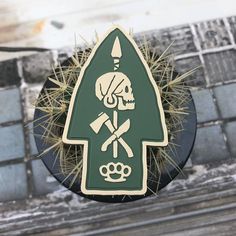 there is a green sign with a skull and cross bones on it in front of a cactus