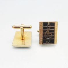 two cufflinks with music notes on them, one gold and the other black