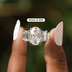 a woman's hand holding an engagement ring with three baguettes on it