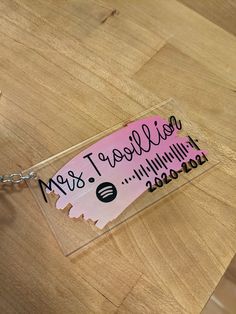 a wooden table topped with a keychain and a piece of pink sticker