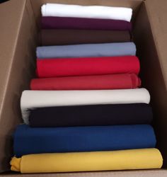 folded sheets in a cardboard box on top of each other, all different colors and sizes