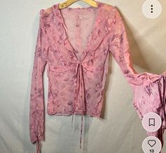 a pink blouse hanging on a hanger next to a white wall with an image of a woman's breast