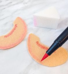 two sponges and a pen sitting on top of a white counter next to each other