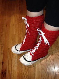 a person wearing red and white crocheted shoes on top of a wooden floor