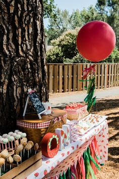 a table topped with cupcakes next to a tree