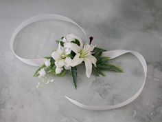 white flowers and greenery are tied to a ribbon on a marble surface with water droplets