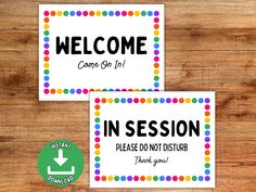 two signs with the words welcome and in session, on top of a wooden table