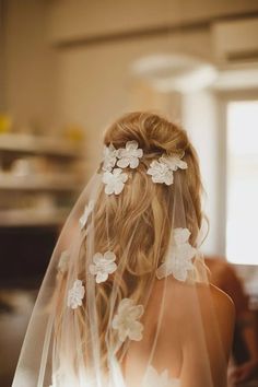 the back of a bride's head wearing a veil with white flowers on it