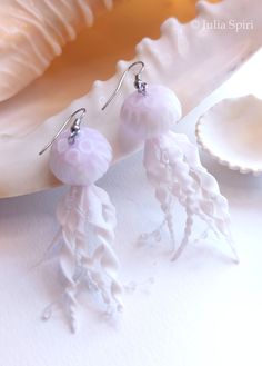 two jellyfish earrings are sitting on a seashell