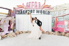 Love lights up the night! 💖 A radiant couple shares a romantic embrace amidst vintage neon signs. The bride's elegant wedding dress flows beautifully, her bouquet raised high, while the groom's classic black tux adds timeless charm. This unique backdrop featuring vibrant lights and eclectic signage makes for unforgettable wedding ideas! Explore the charm of neon museum weddings. Museum Weddings, Unique Backdrop, Vintage Neon