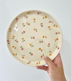 a hand holding a plate with flowers on it