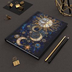 an open notebook sitting on top of a table next to some gold and black items