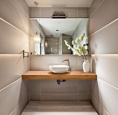 a bathroom sink sitting under a mirror next to a vase with flowers on top of it