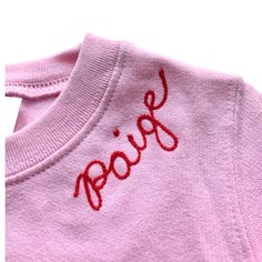 a pink shirt with the word poop embroidered on it